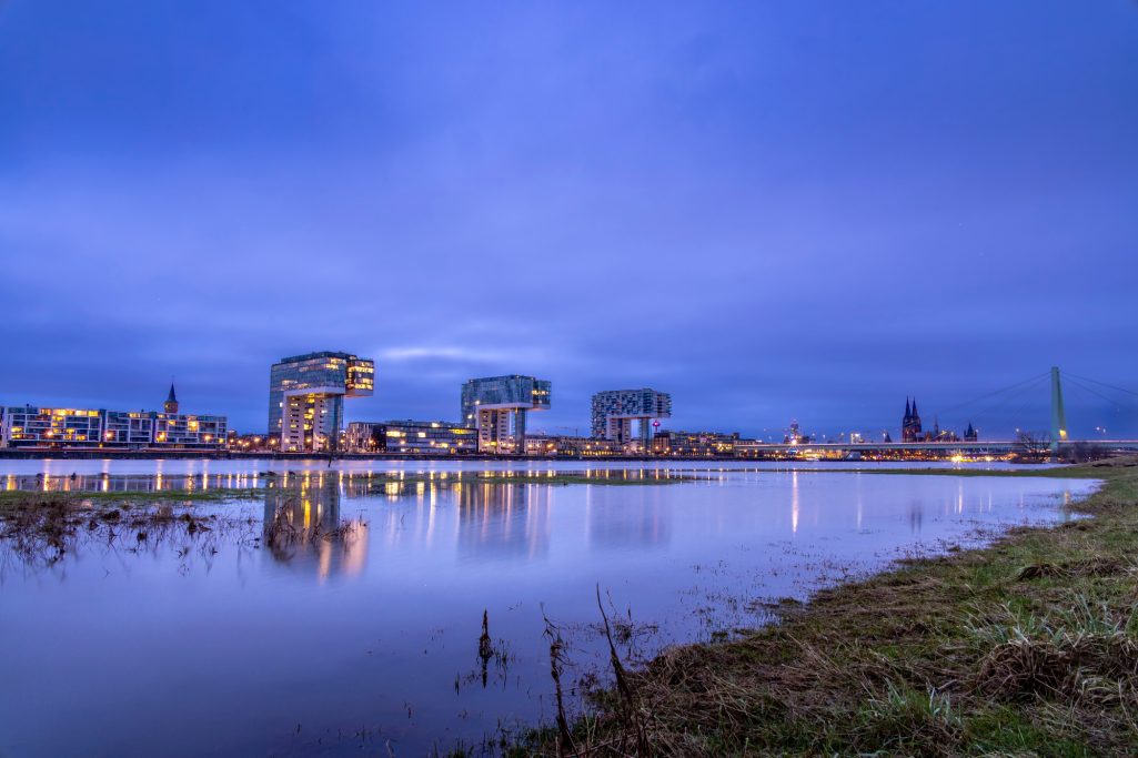 Städtische Landschaft bei Dämmerung mit reflektierenden Gebäuden am Wasser.