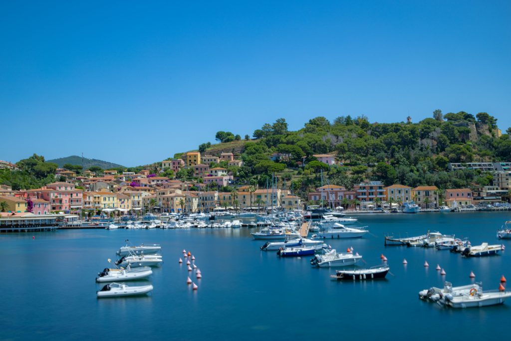 View of a harbour with many boats and colorful houses on the shore.