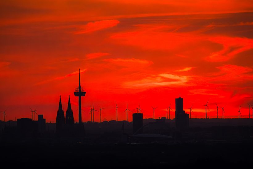 Silhouette of city buildings against a bright red sunset.