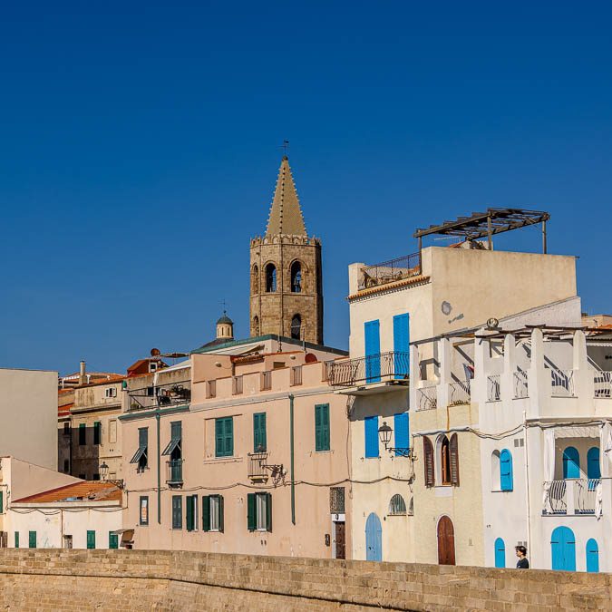 Colorful building with blue painted windows and a church tower in the background.