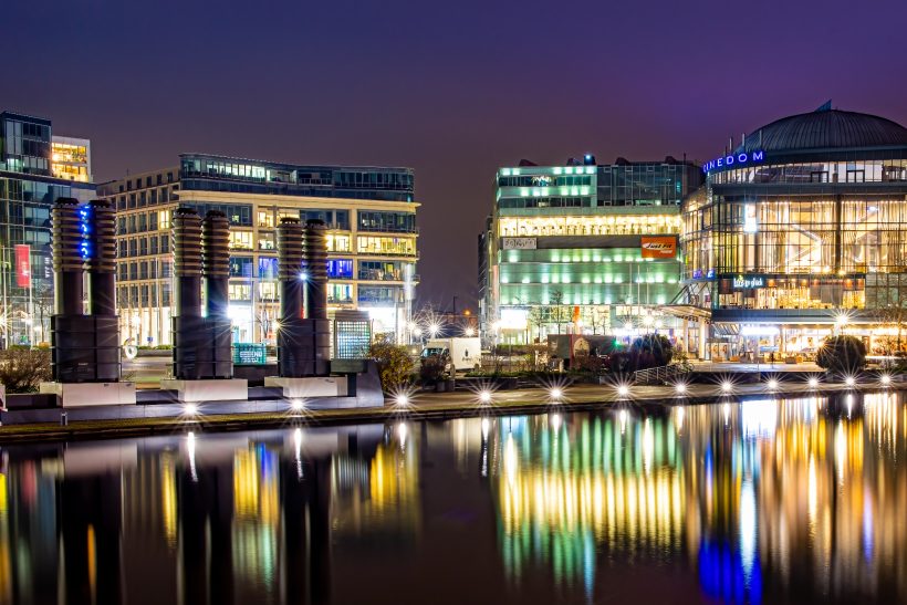 City view at night with illuminated water and modern buildings.