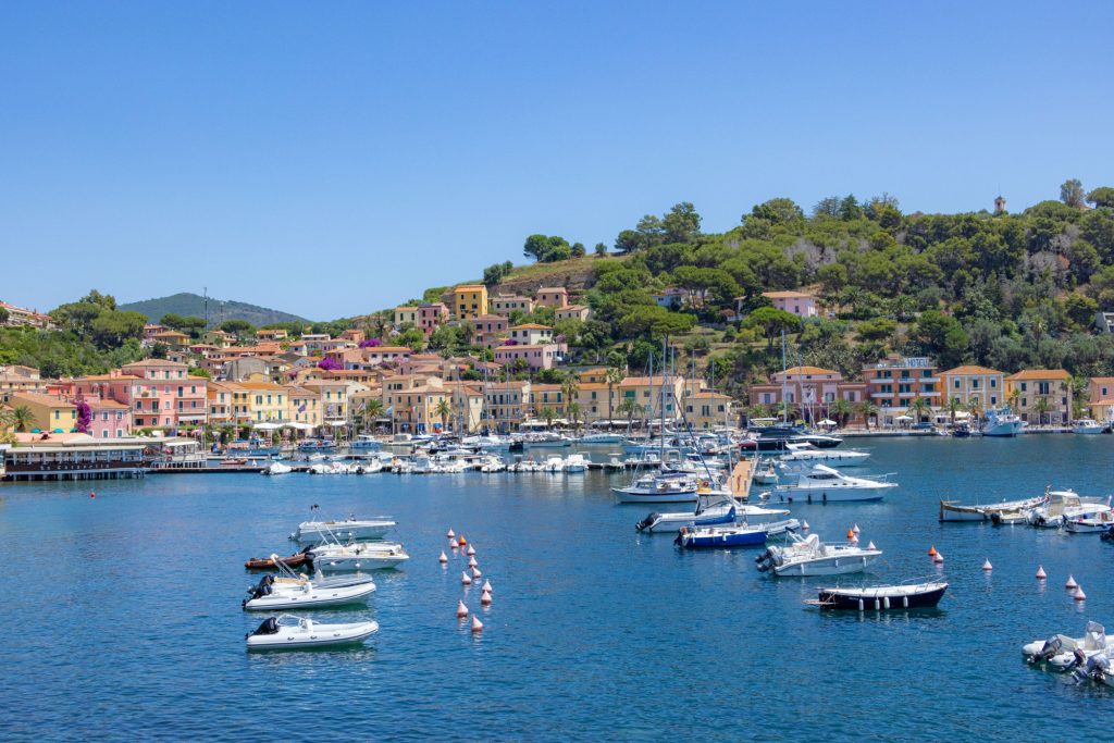 Colorful boats in the sparkly waters of a picturesque coastal village under blue sky.