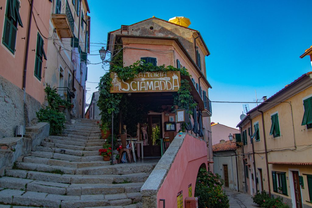 Gemütliches Restaurant in einer gepflasterten Straße mit bunten Häusern und Pflanzen.