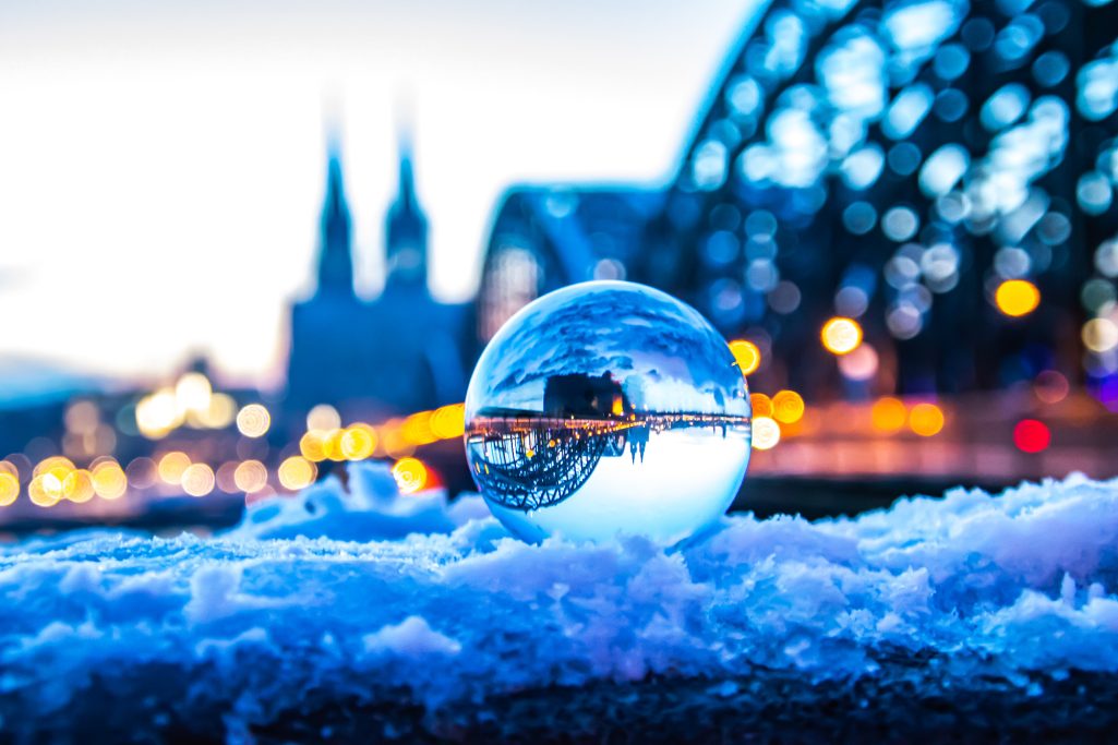 Crystal ball reflects the Cologne skyline and a snow-capped environment.