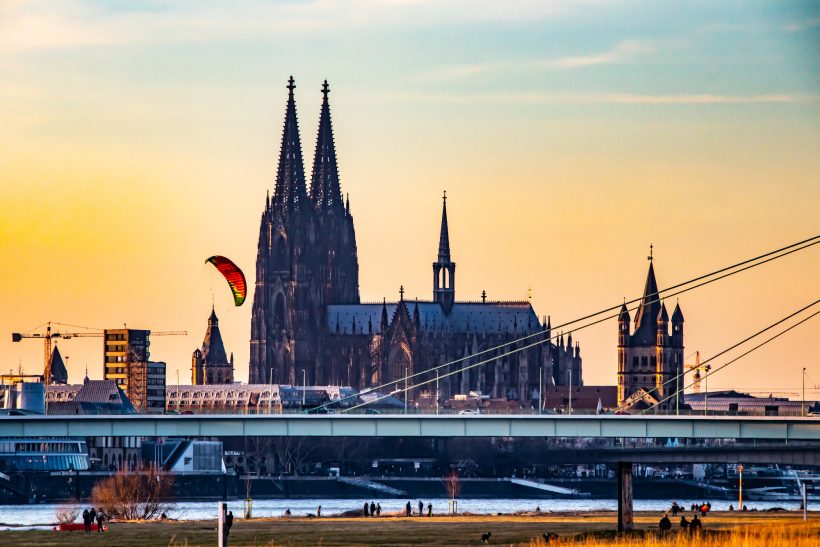 Kölner Dom bei Sonnenuntergang mit einem Gleitschirmflieger im Vordergrund.