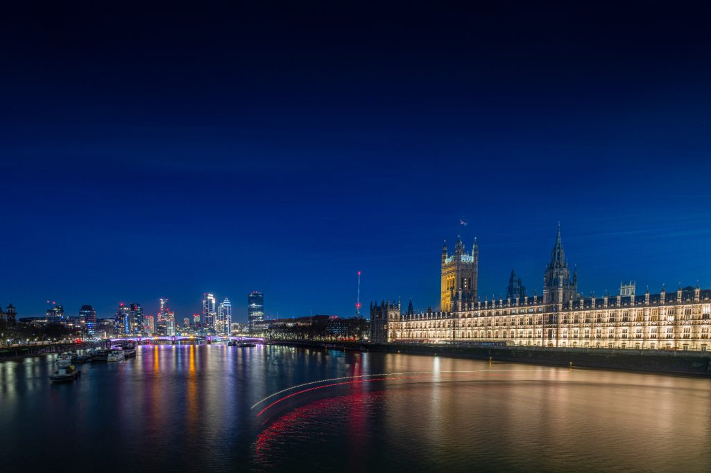 View of the British parliament and the Thames at night with illuminated skies.