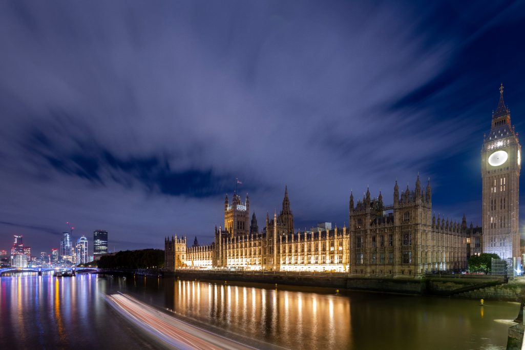 The Parliament building and Big Ben at night, reflecting in the water of the Thames.