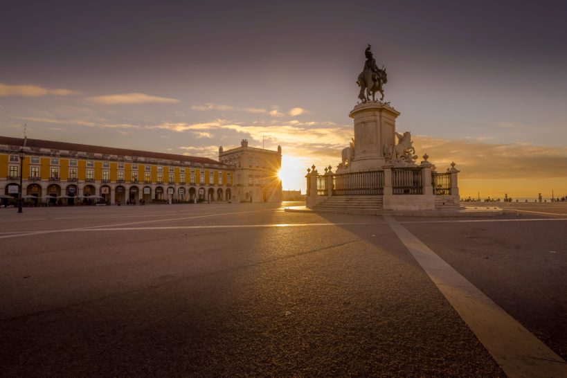 Magnificent statue in front of a historic facade in the sunset.