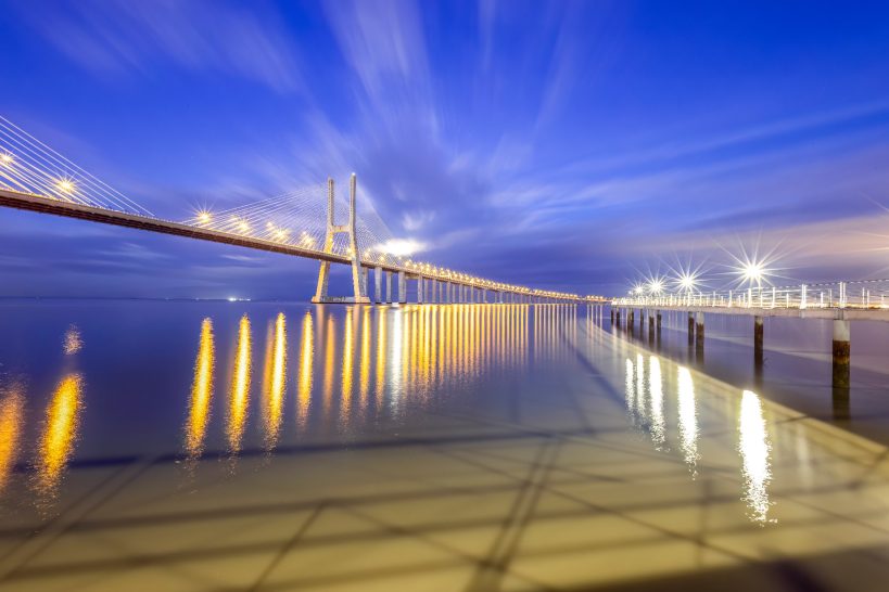 Brücke bei Nacht mit sanftem Lichtreflexionen auf dem Wasser.