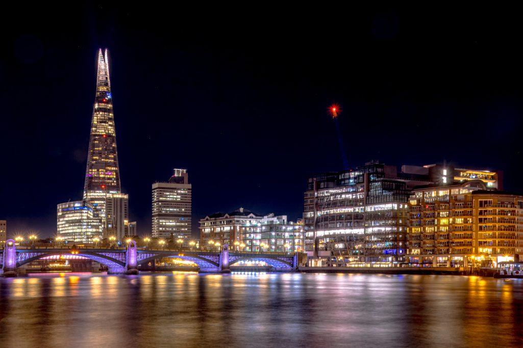 Night view of the Thames with the Shard and illuminated buildings in the background.