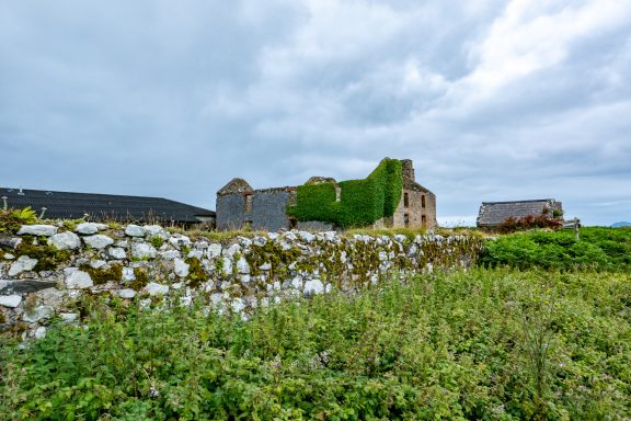 Quiet, historic building with a green facade and overgrown stone walls.