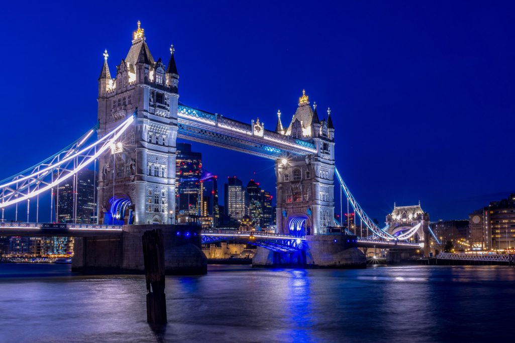 Tower Bridge in London at night, illuminated with blue and white lights.