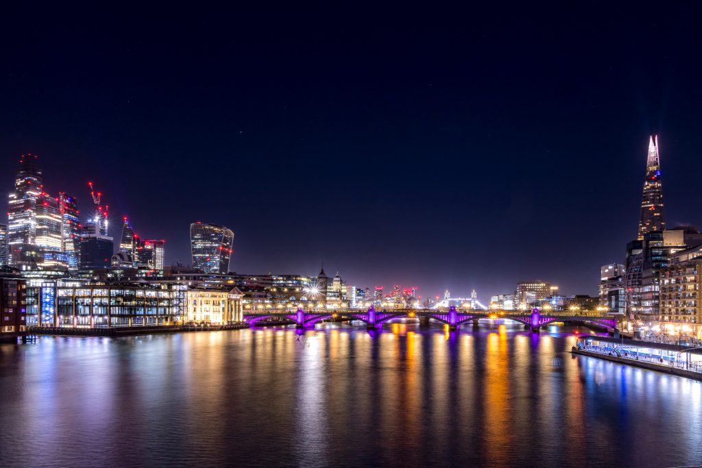 Night view of the London skyline with illuminated Thames and bridges.