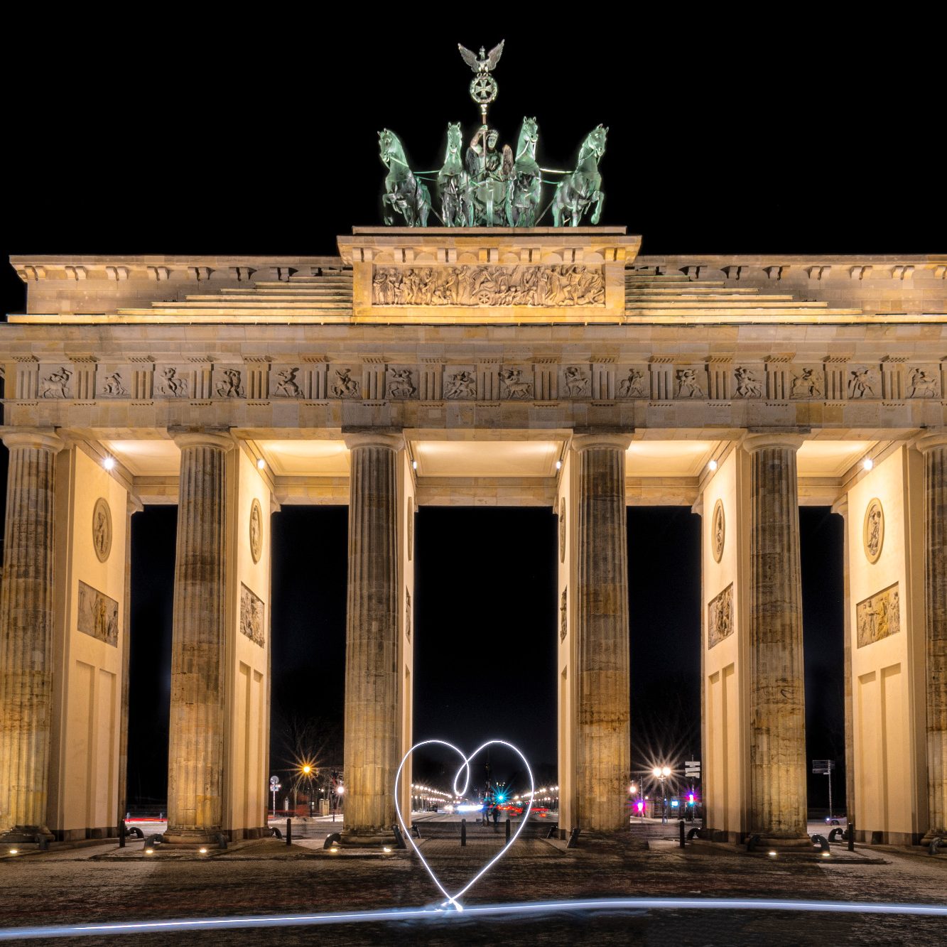 Das Brandenburger Tor bei Nacht, beleuchtet mit einem Herzen im Vordergrund.