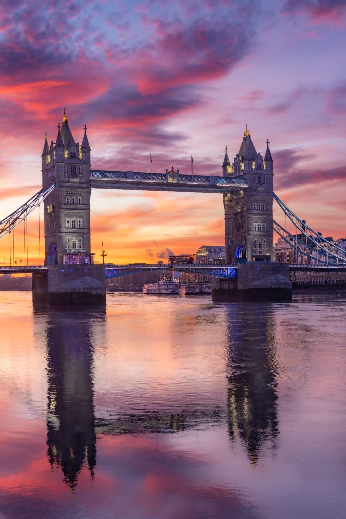 The Tower Bridge in front of a colorful sunrise over the water.