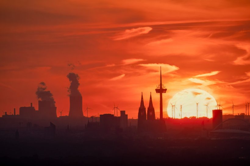 Silhouettes of buildings in front of a bright sunset in orange-red colors.