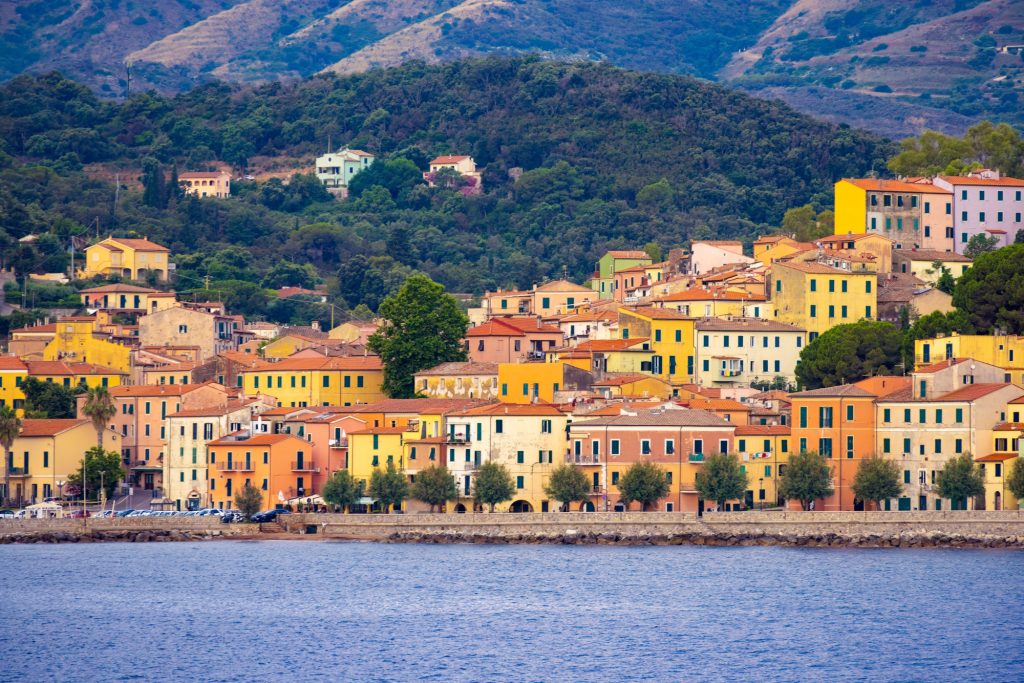 Colorful houses on the shore with views of rolling hills in the background.