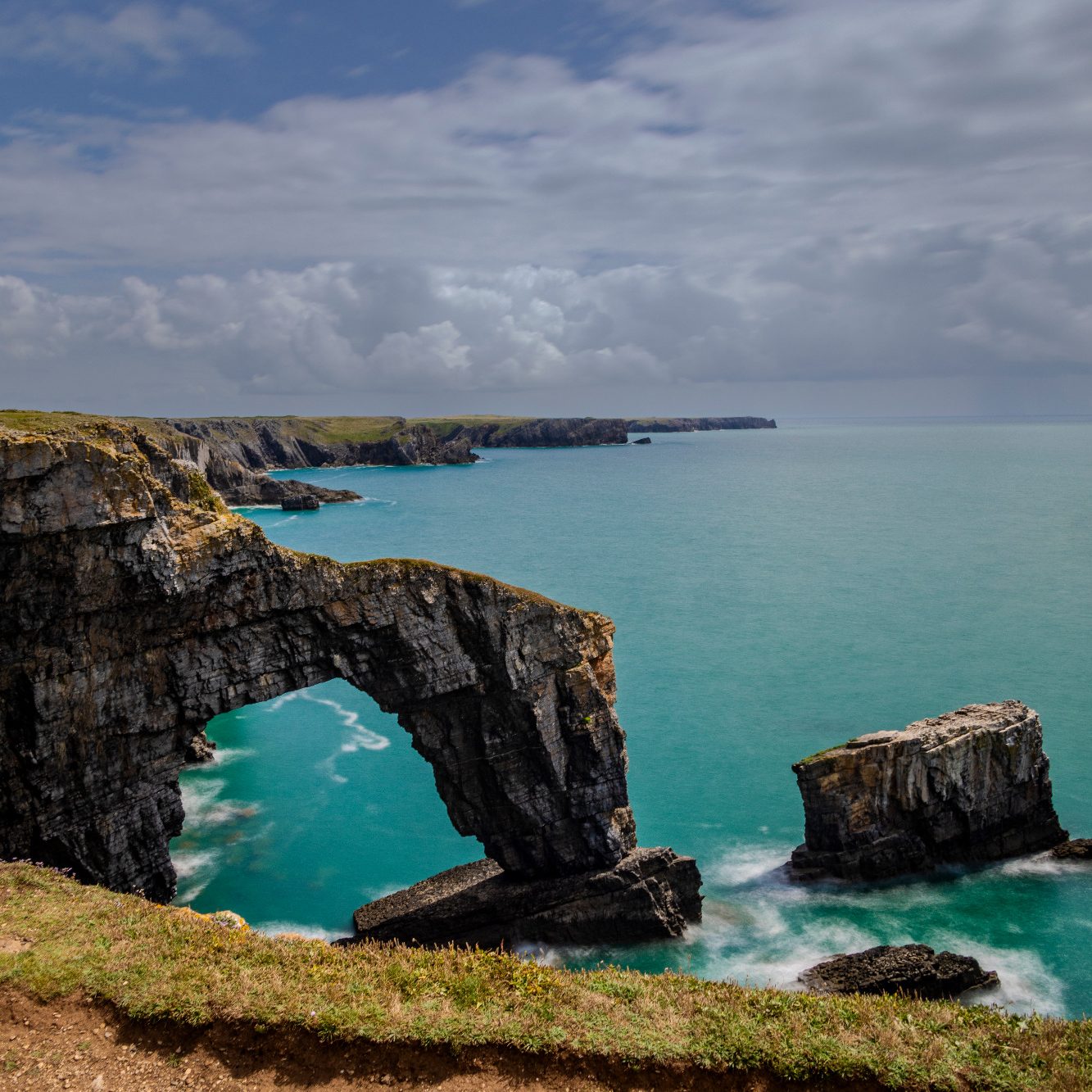 Coastal landscape with steep cliffs and a natural rock arch.