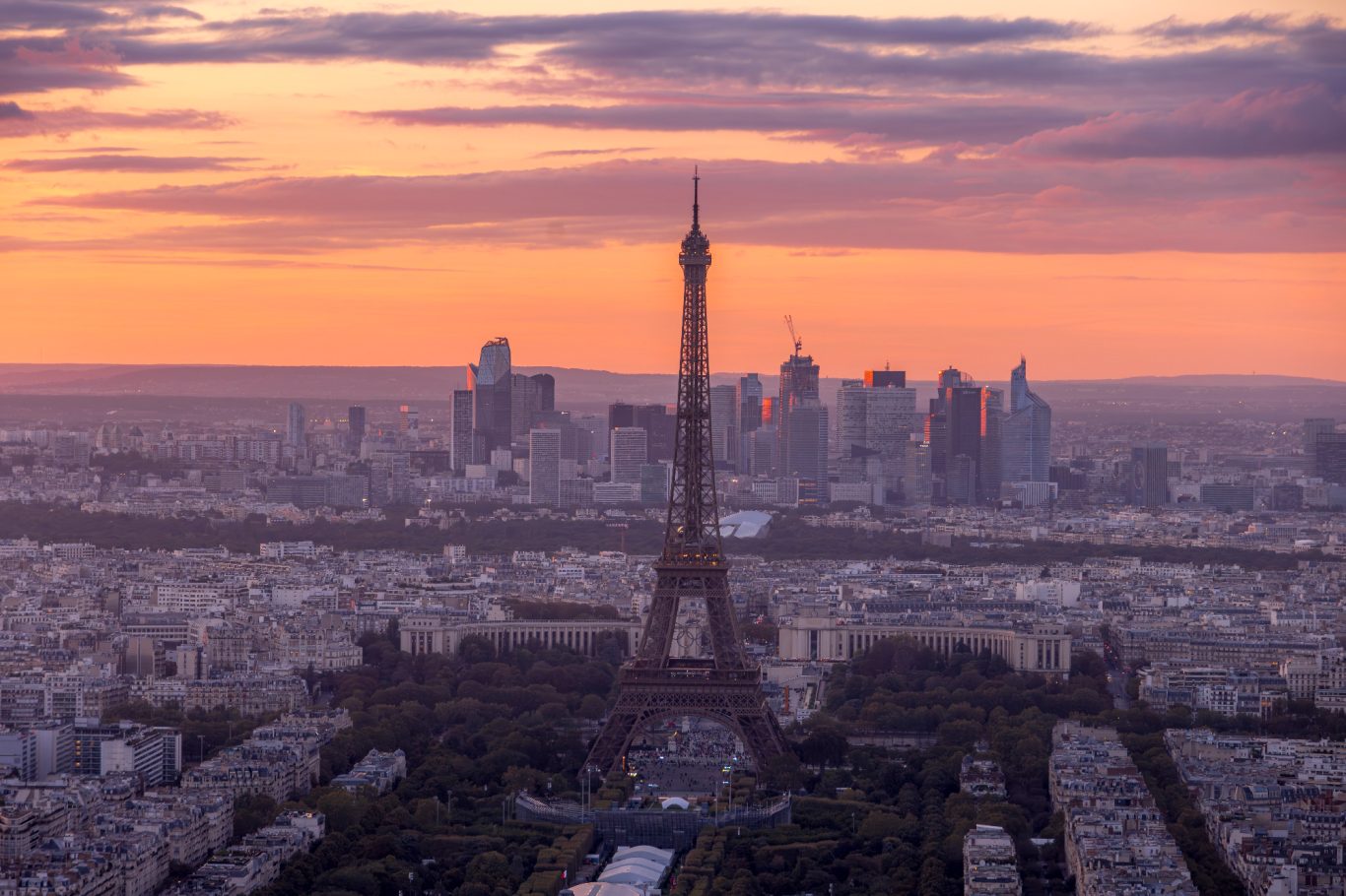 Eiffel Tower with skyline of Paris at sunset in the background.