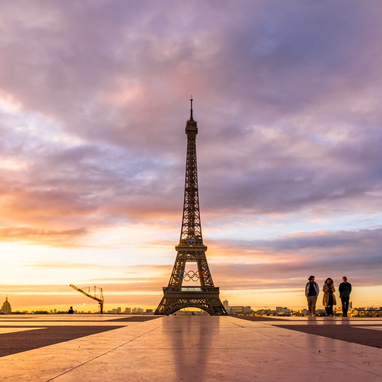 The Eiffel Tower at sunrise with silhouettes of people in the foreground.