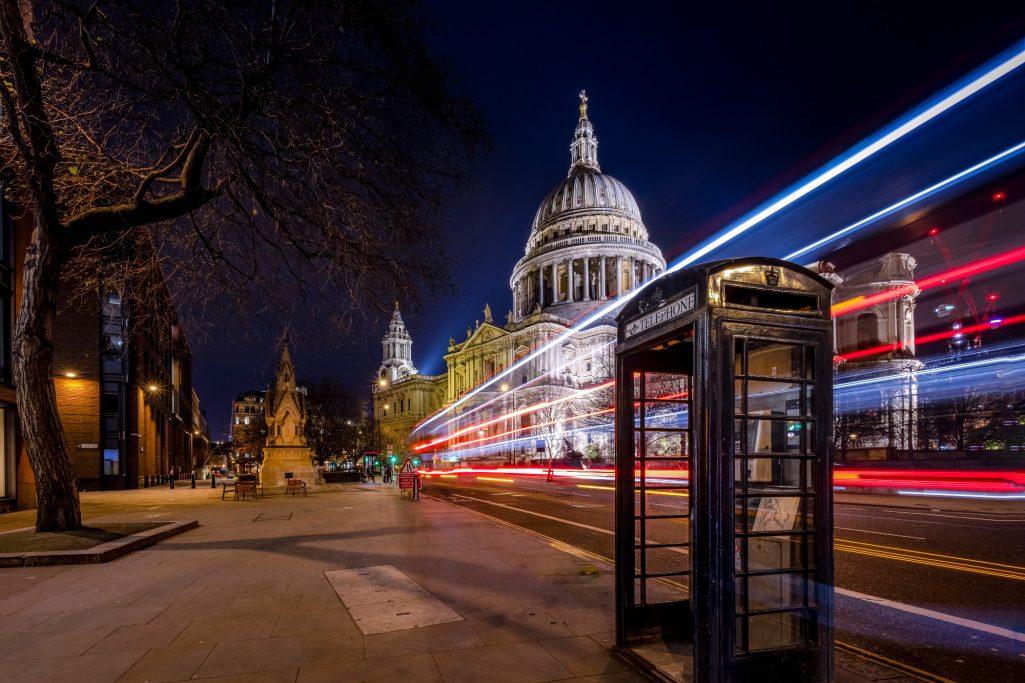 Nachtansicht von St. Paul's Cathedral mit einer Telefonzelle und Lichtspuren von Bussen.