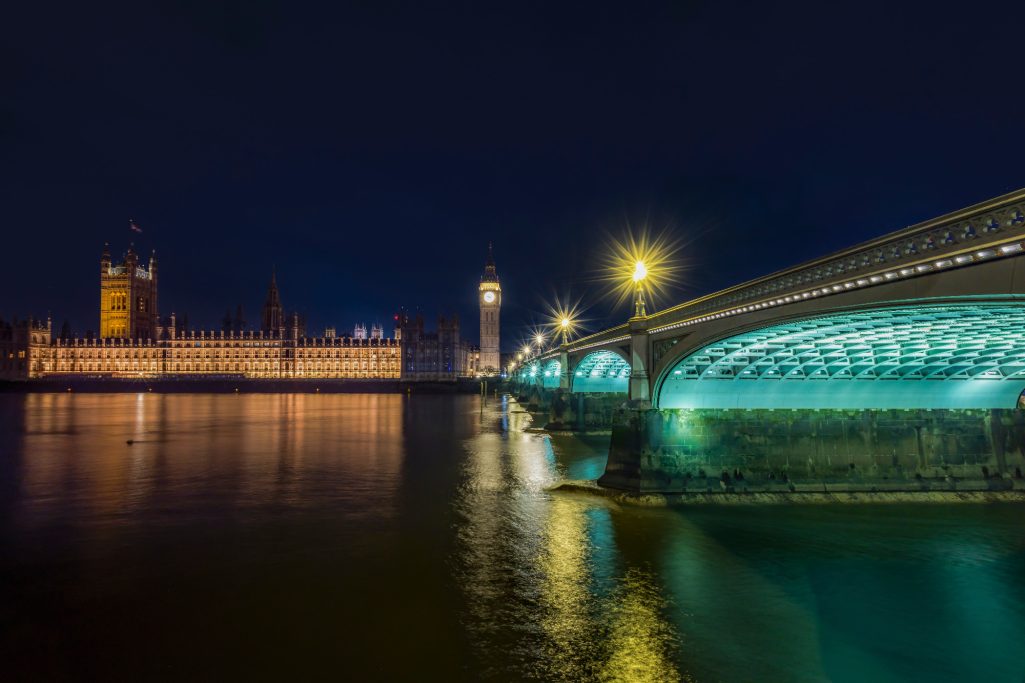 Nachtaufnahme der Houses of Parliament und der beleuchteten Brücke über der Themse.