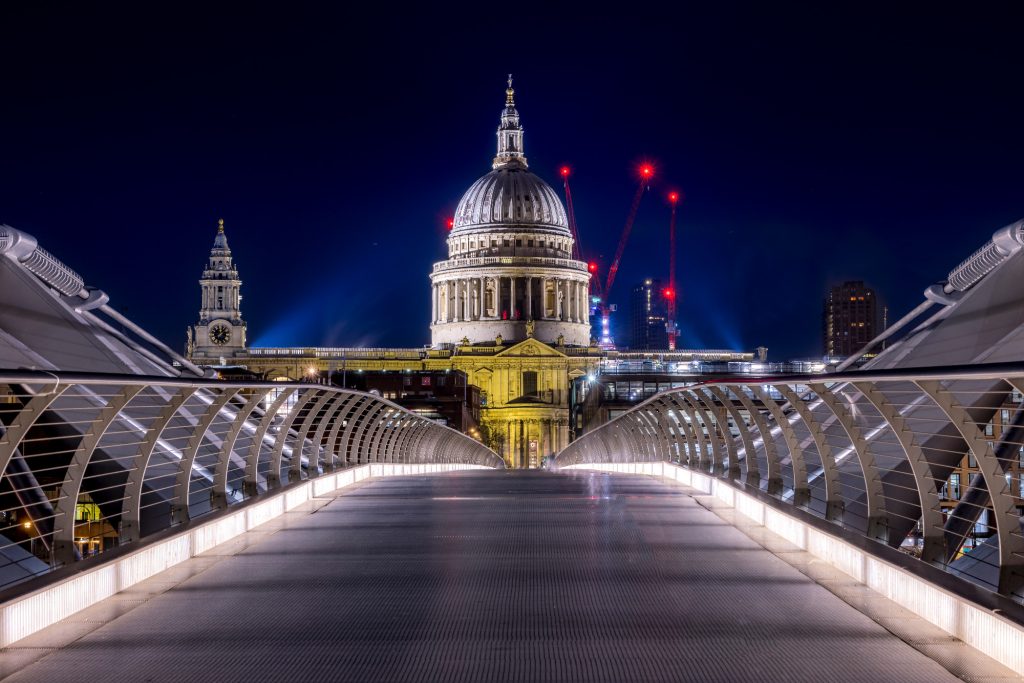 St. Paul's Cathedral at night, illuminated, with modern bridge in the foreground.