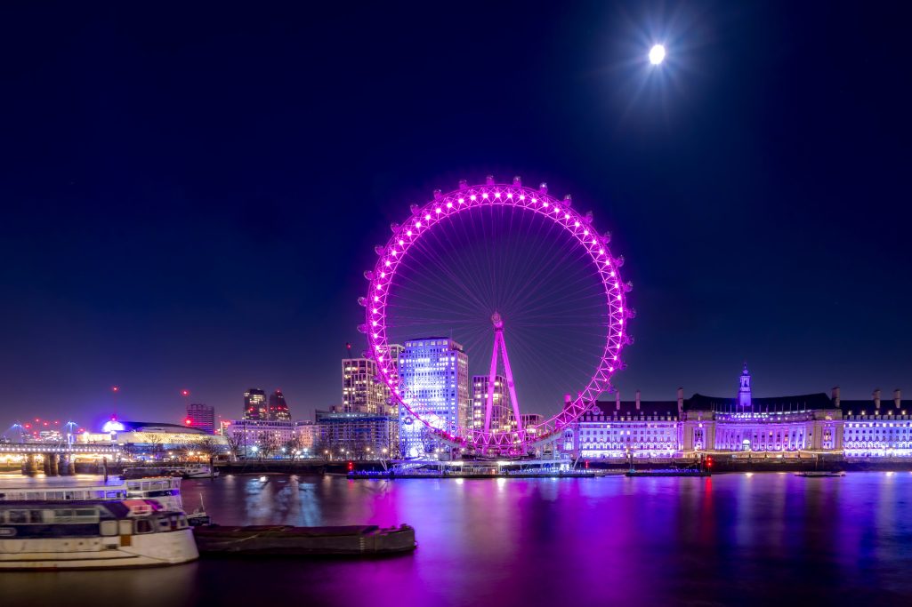 London Eye bei Nacht mit lila Beleuchtung und klarem Himmel.