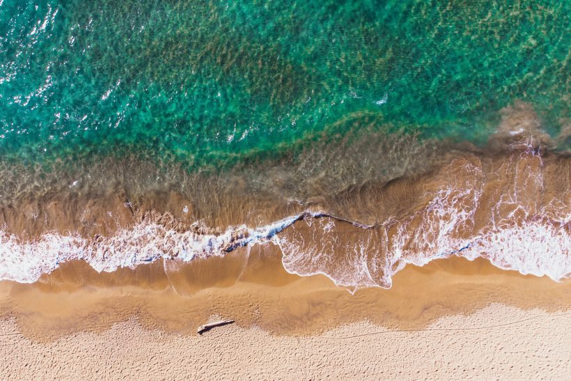 Turquoise water meets a sandy beach with gentle waves.