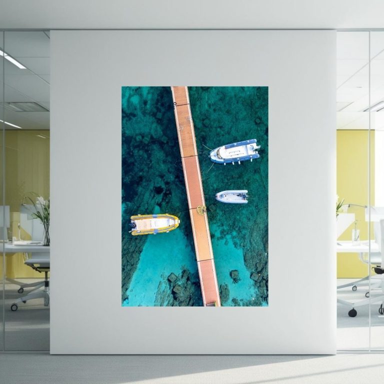 A wooden bridge over turquoise water with boats nearby.