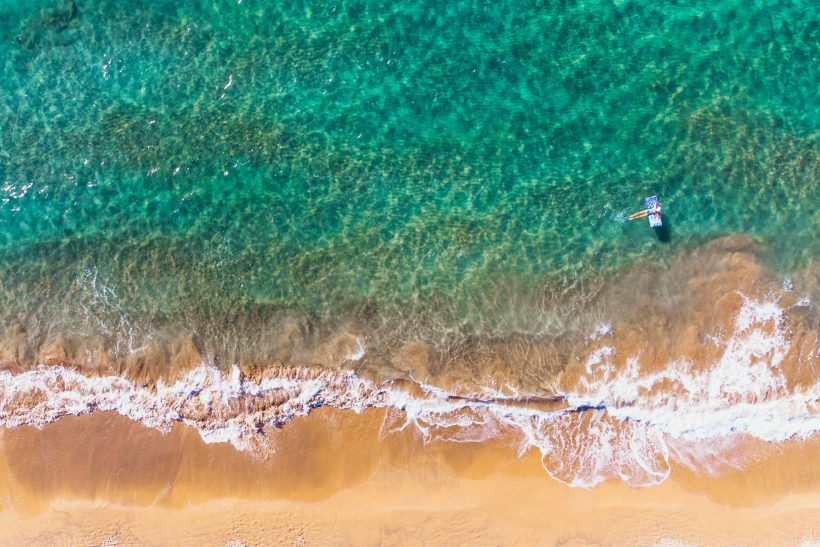 Klares, türkisfarbenes Wasser trifft auf einen goldenen Sandstrand.