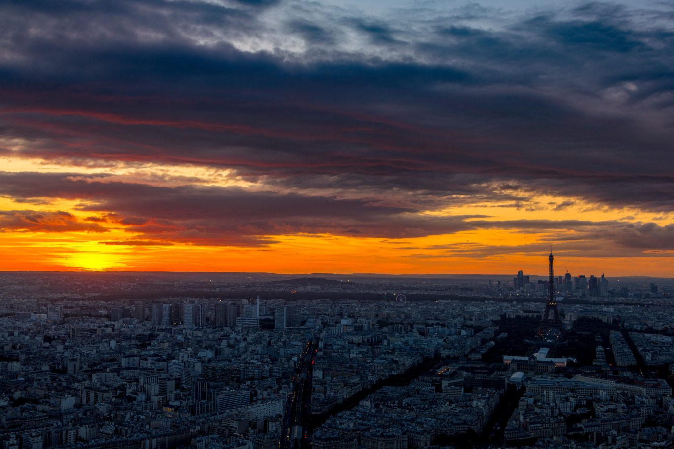 Sonnenuntergang über Paris mit Wolken und Stadtansicht im Hintergrund.