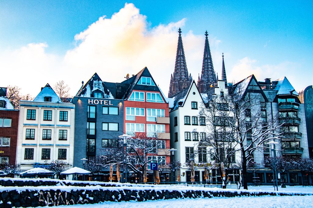 Colorful row of houses with pointed roofs in front of a bright blue sky in the snow.