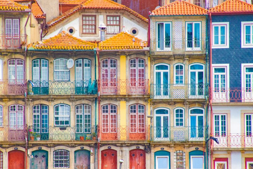 Colourful facades with bay windows and red roofs in an urban environment.