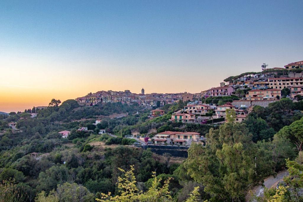 Panoramablick auf ein malerisches Dorf mit sanften Hügeln und Sonnenuntergang.