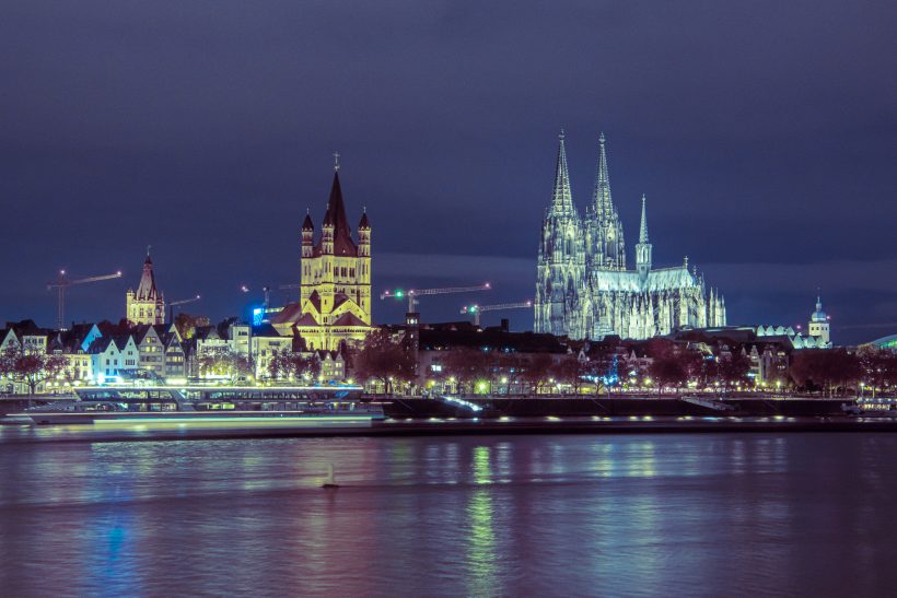 Kölner Skyline bei Nacht mit dem Kölner Dom und beleuchteten Uferpromenaden.