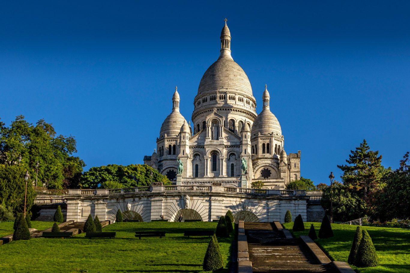 The Sacré-Coeur Basilica on the hill of Montmartre in Paris, surrounded by gardens.