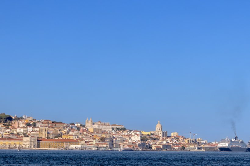 View of the coast with a city, blue sky and shimmering water.